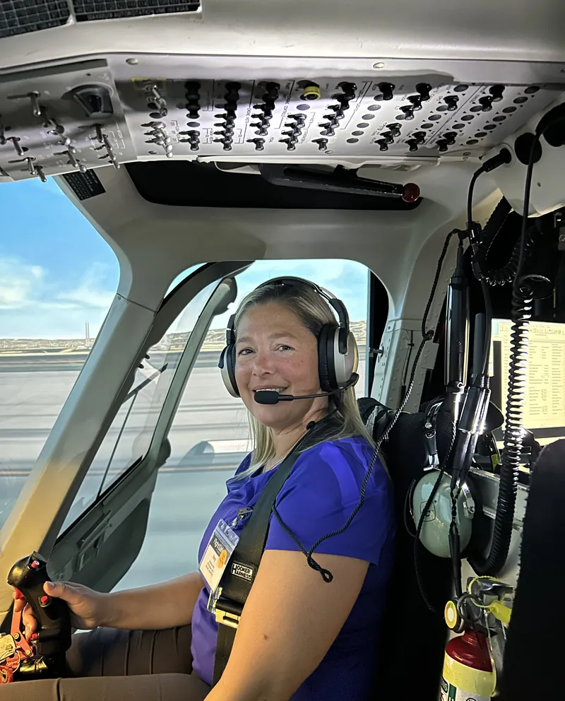 Amy Hartt smiling in a headset in the seat of a Bell 407 flight training device at FlightSafety International.