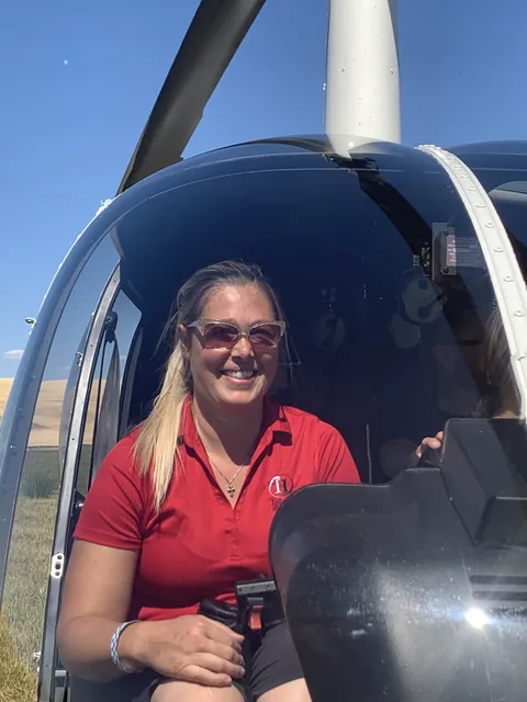 Amy Hartt smiling in a helicopter seat in her red Inland Helicopters polo.